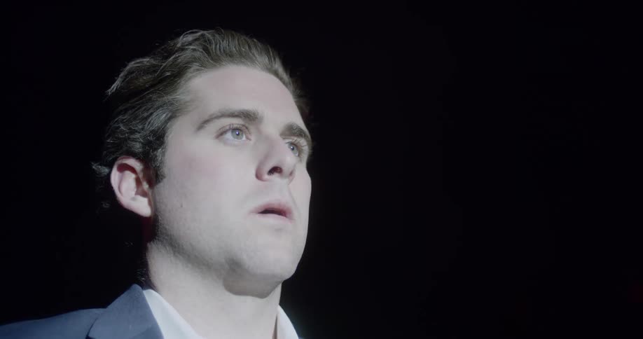Man raises his head and looks at the source of the light by exhaling on the stage