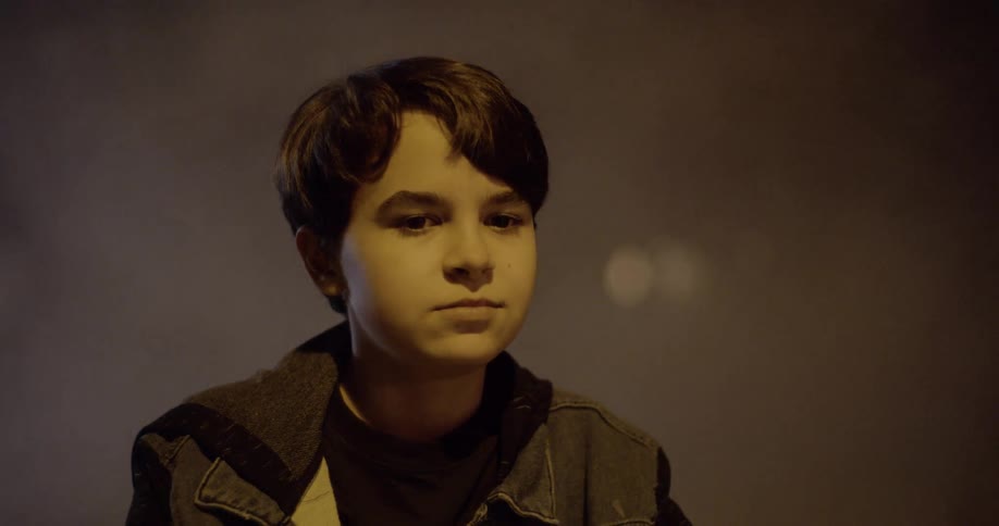 A boy shakes his head on a dark foggy night
