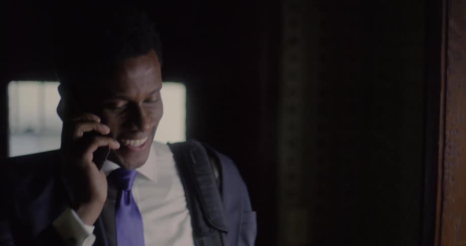 A man walks through a door talking on a cell phone