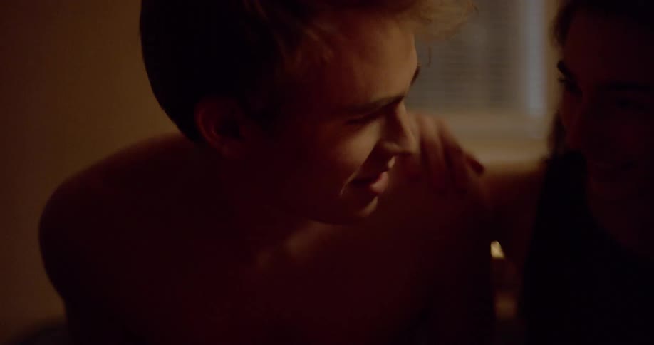 A young girl rests her hand on a boys shoulder and they lean in close and talk