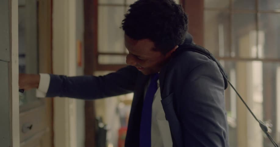 A man holds a cell phone with his ear and shoulder while unlocking his front door