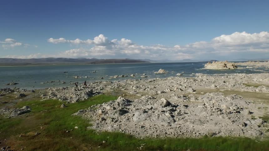 People are traveling over some rocks by the coast