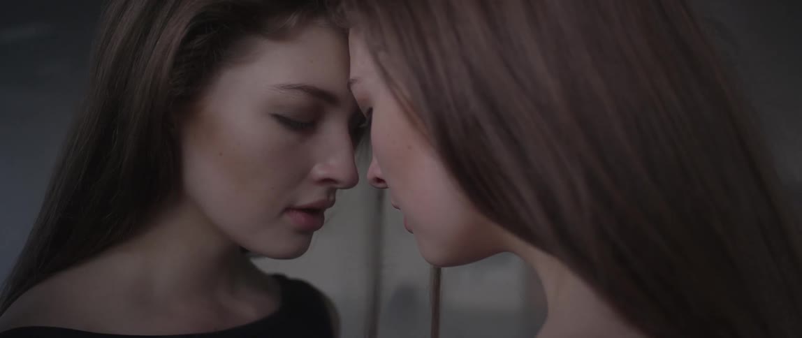 A woman leans her head against a mirror and breathes deeply