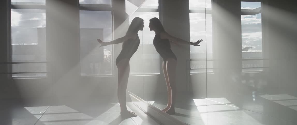 A woman is stretching in front of a large mirror