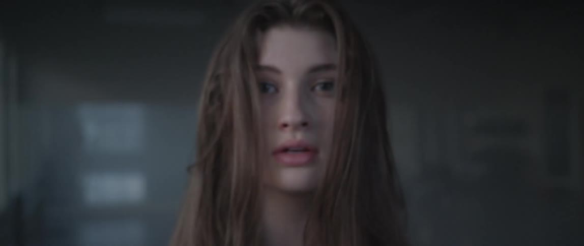A woman slowly looks up and center walking back