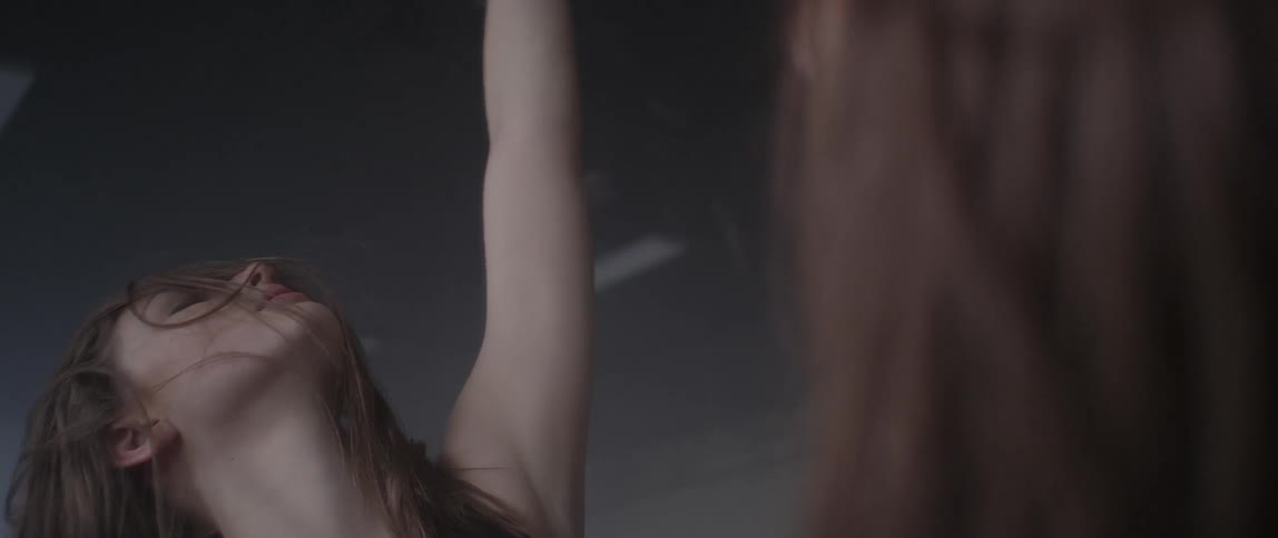 A woman with long brown hair dances in front of a mirror