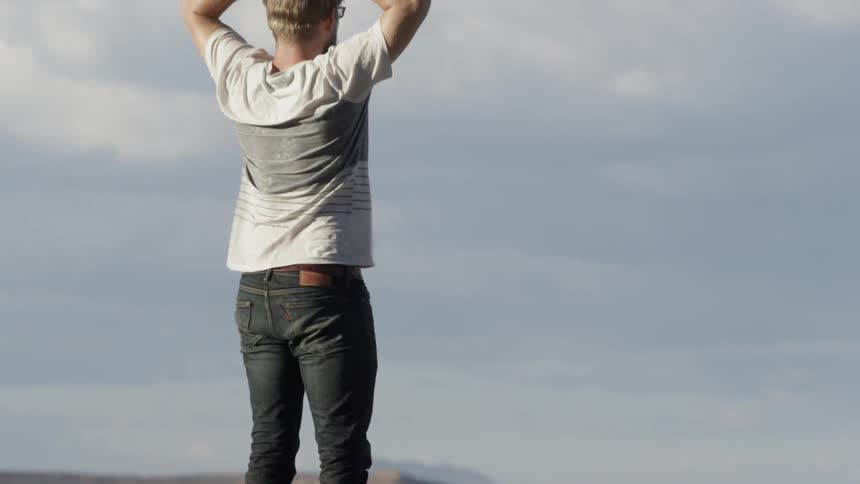 A man stands on a mountain ridge on a windy day
