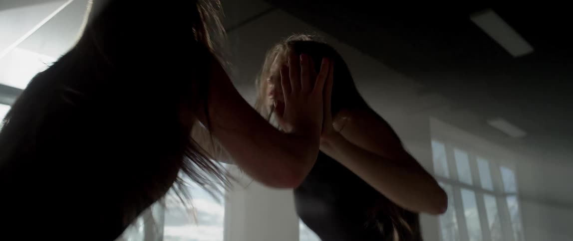 A woman dancing in front of a large mirror