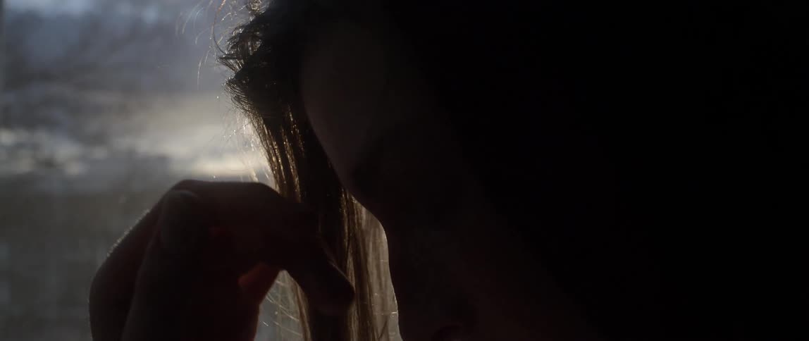 A woman moves her hand over her face as the sun sets