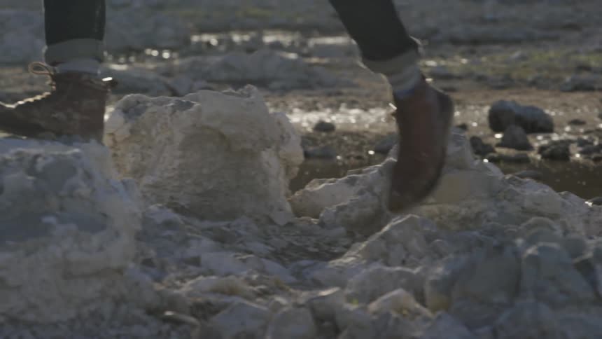 People are walking over some rocks by a small stream