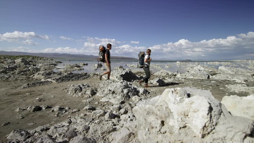 Hikers crossing muddy, rocky terrain