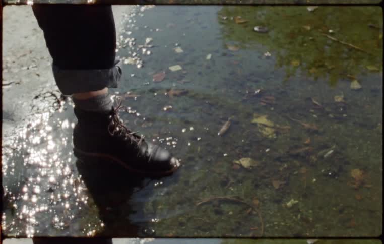 A woman steps her foot in to a puddle