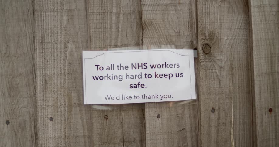A sign thanking national health service workers taped to a wooden fence