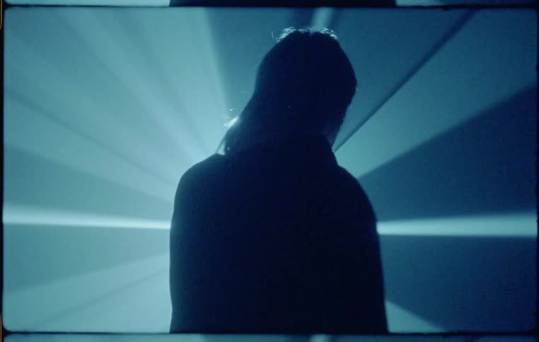 A person stumbling in a dark room with a light shining on their face