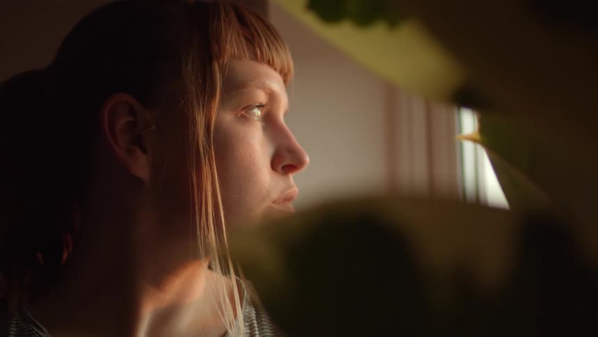 Woman looks out the window at dusk