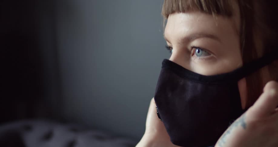 A woman putting on a face mask indoors