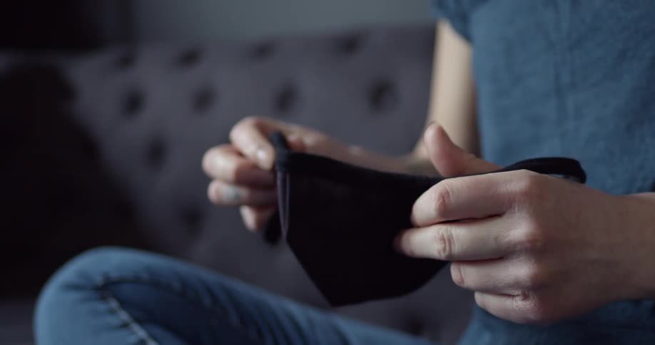 A person sitting on a couch holding a mask