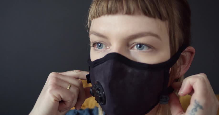 A woman sitting on a chair putting on a face mask