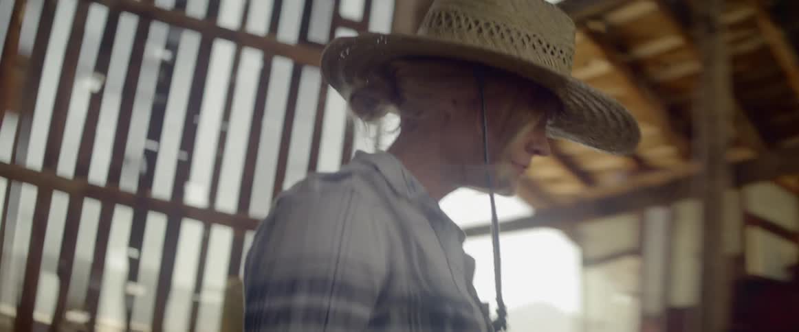 Female rancher lifting and stacking hale bails to other side of barn