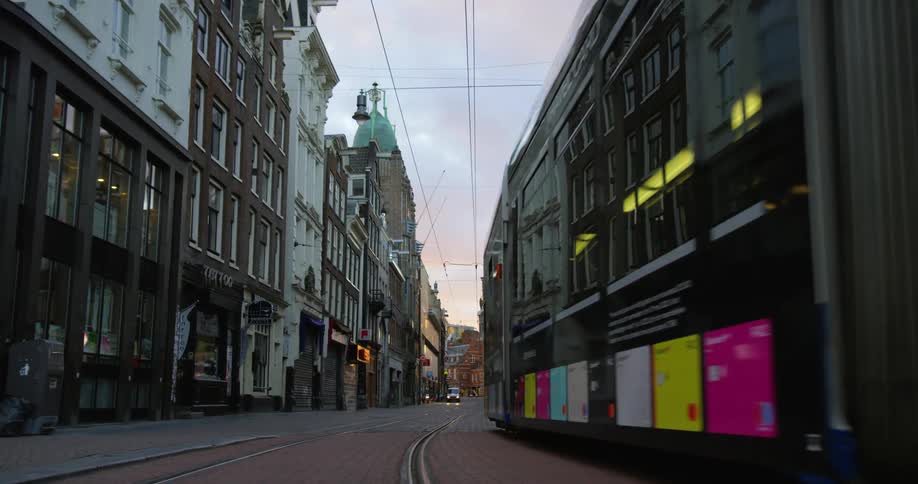 A city trolley traveling down a city street with buildings on both sides