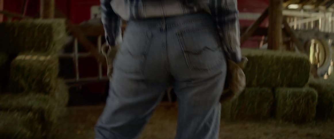 A woman carries hay bails