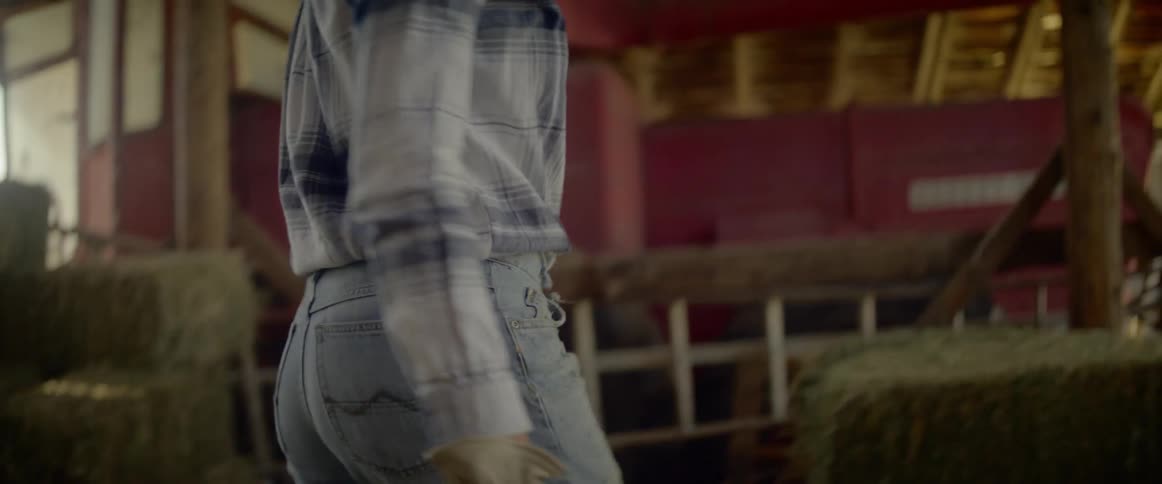 Woman carries a bale of hay in the barn