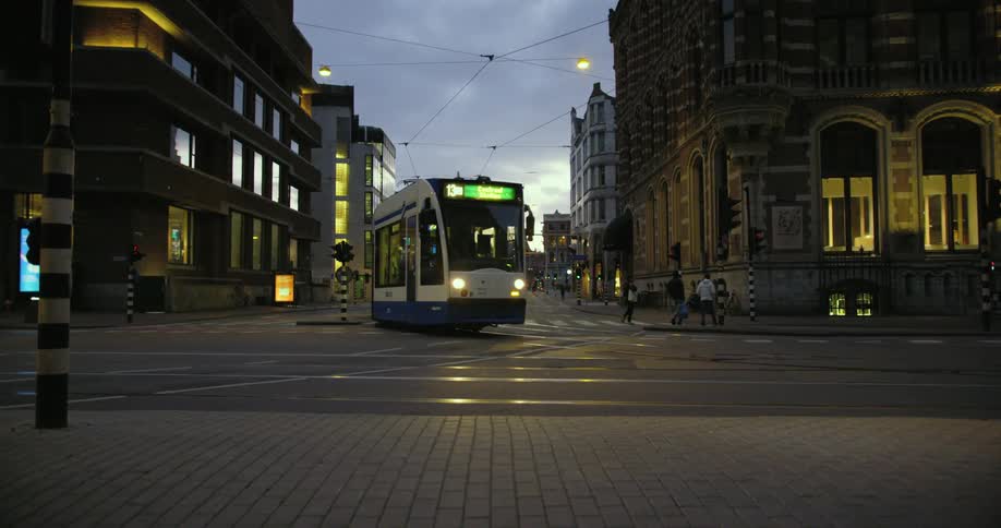 Three people crossing the street as a trolley rides by