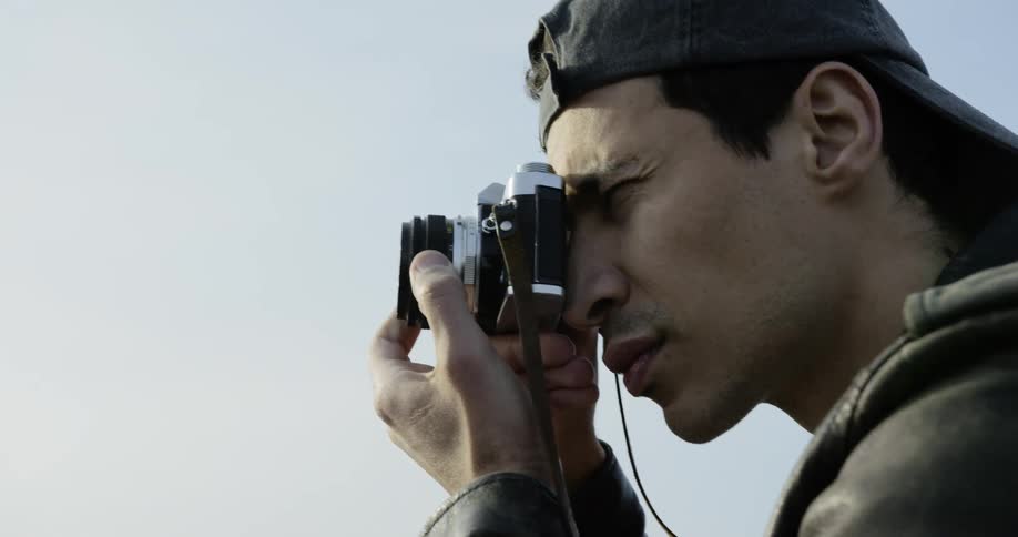 Man adjusts camera as he aims it outdoors