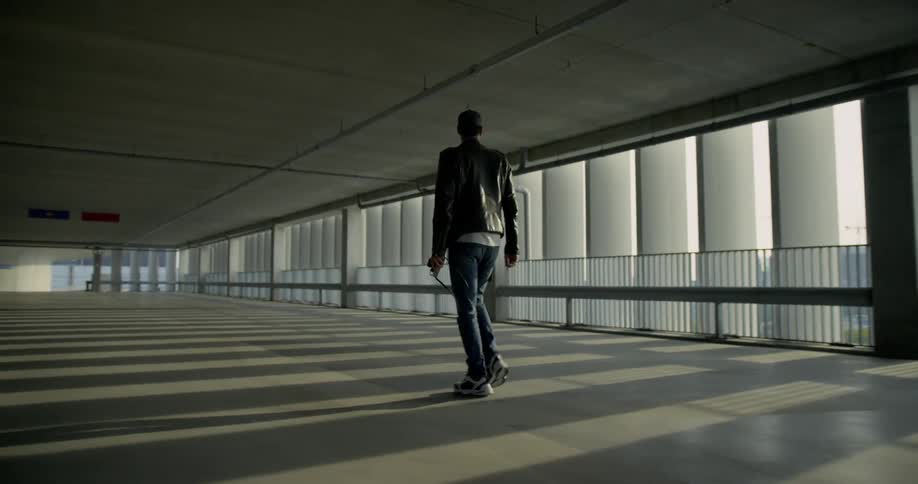 A man walking in an indoor parking lot inside a building