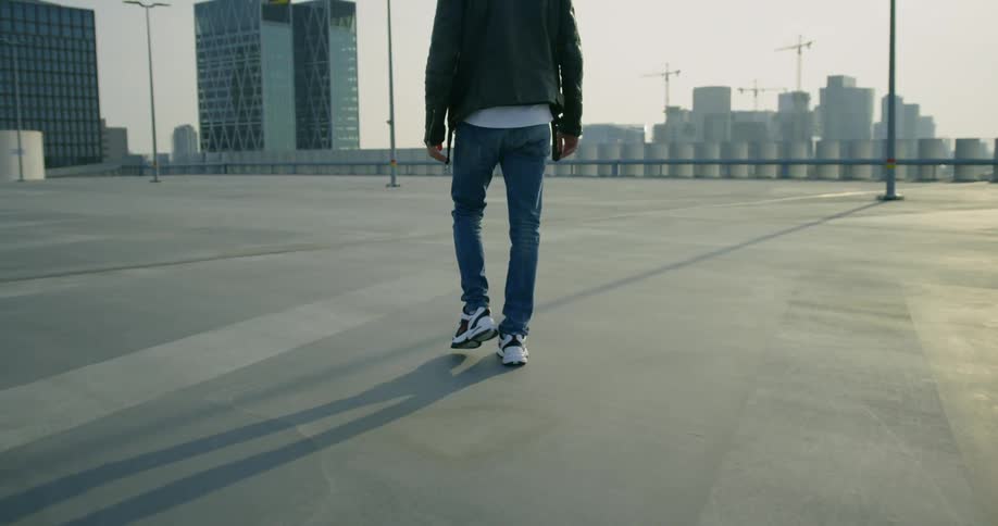 Man walks on the rooftop of big building and looks at the city skyline