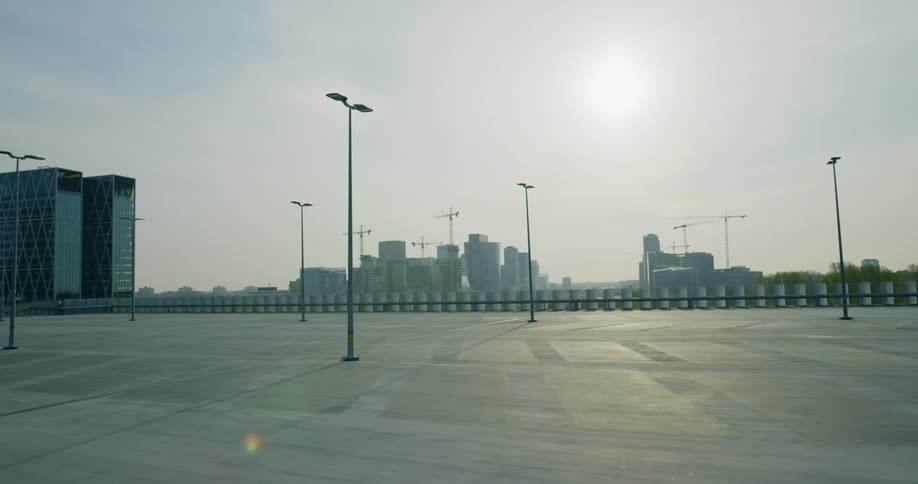 Parking lot stands empty while sun hovers over skyline on horizon