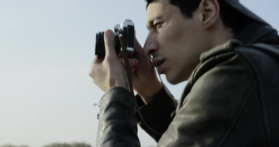 A man adjusts a camera before holding it up to take a photograph