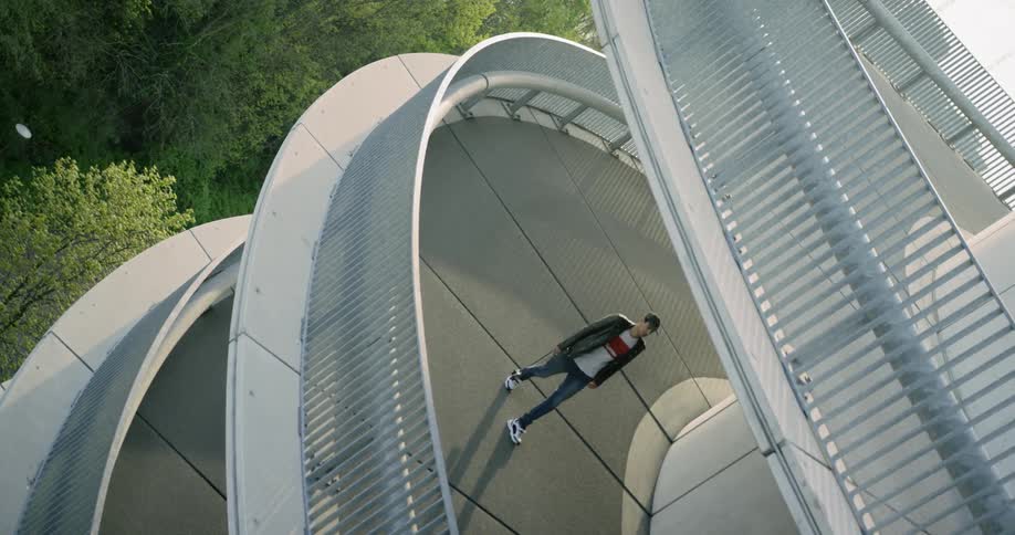 A man carrying a camera by the strap walks up a circular ramp to an observation deck