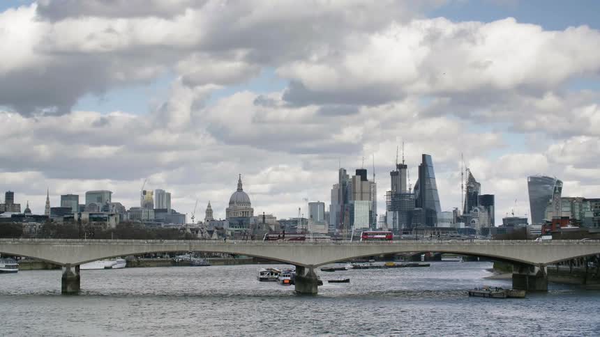 Vehicles cross the bridge in front of the skyline of the city