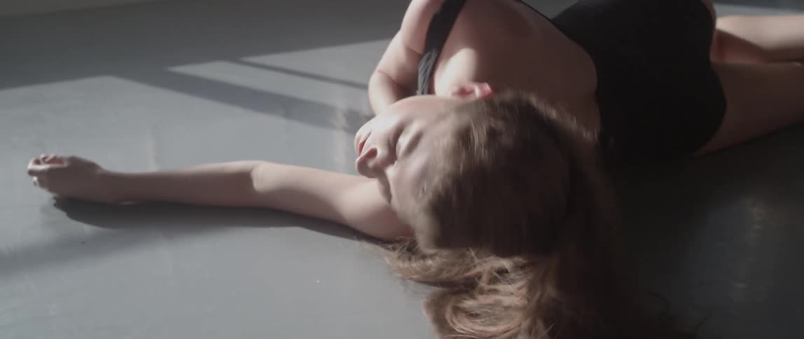 A woman lays and rolls on the floor