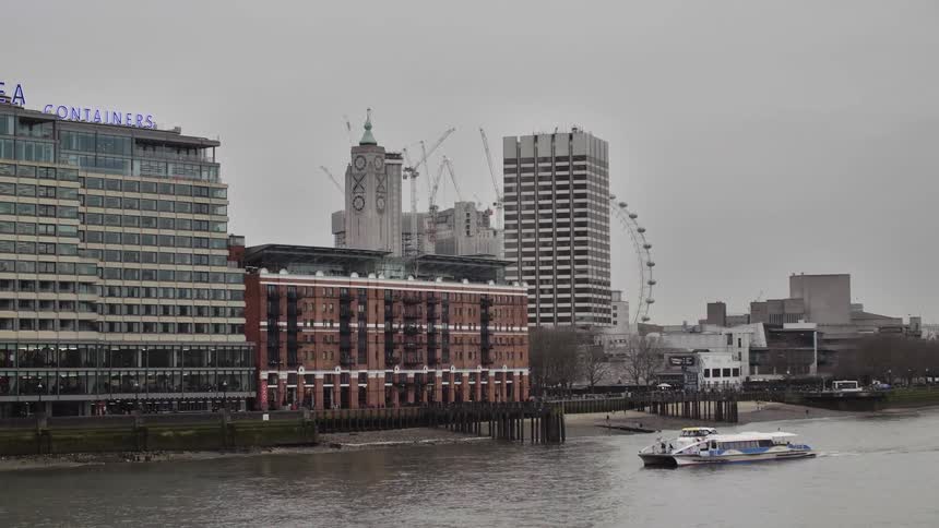 Ferry travels across the river next to the city on a cloudy day