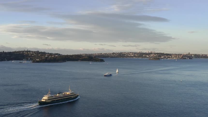 A large ship travels in a harbor towards a city on the shore