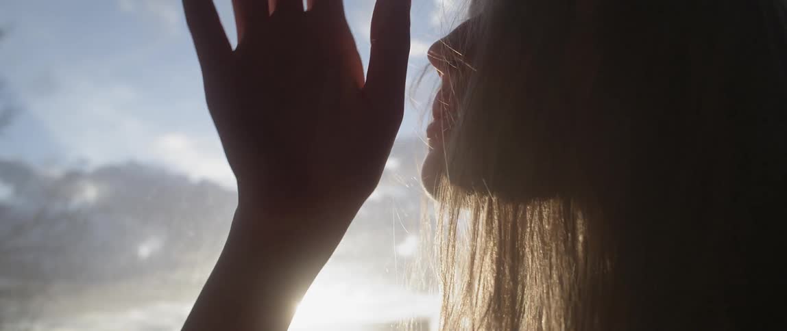 A woman moves her arm down as the sun sets