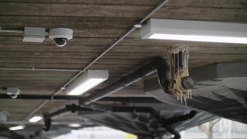 Water drips off pipe coated in caulk that oozed into tendrils