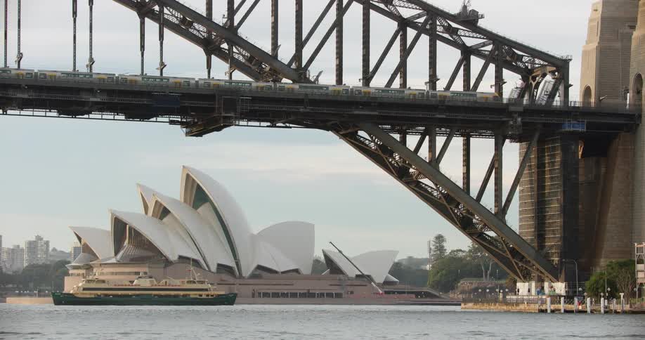 Train crosses suspension bridge near sydney opera house