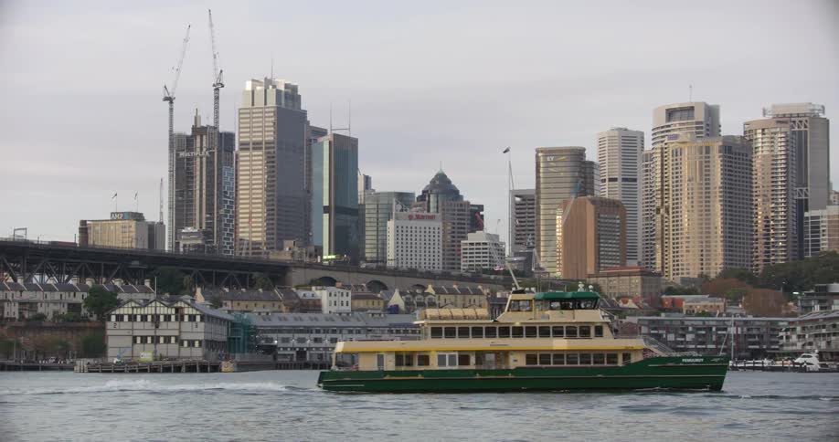A ferry travels through a harbor past the city skyline and waterfront
