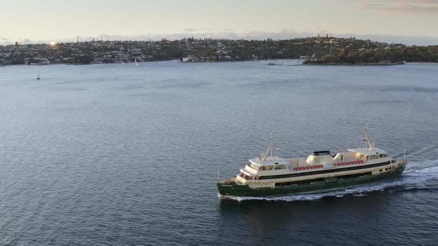 A ferry moves through the water leaving a wake at sunset