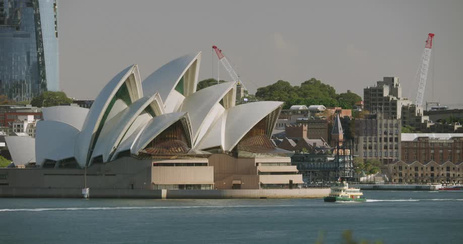A coastal city with boats in the water and an opera house and buildings on the land