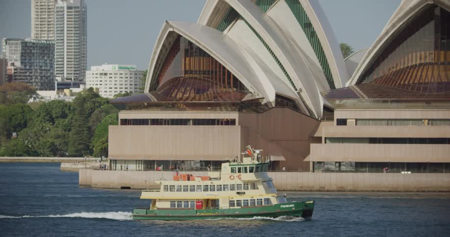 Empty ferry sails on the sea in front of the the sydney opera house