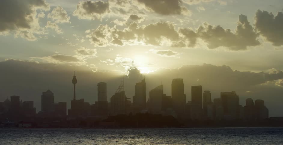 Sun goes down behind the city skyline next to the ocean