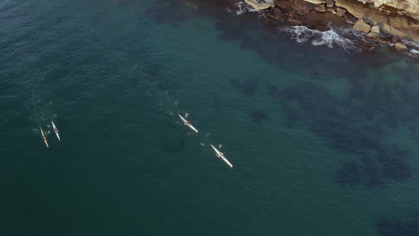 Four people paddle kayaks in the water