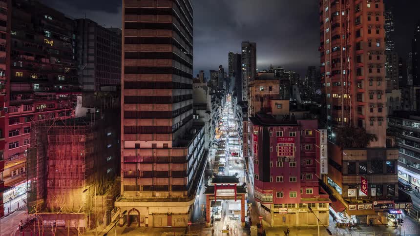 People walk through a chinatown gate in a city at night