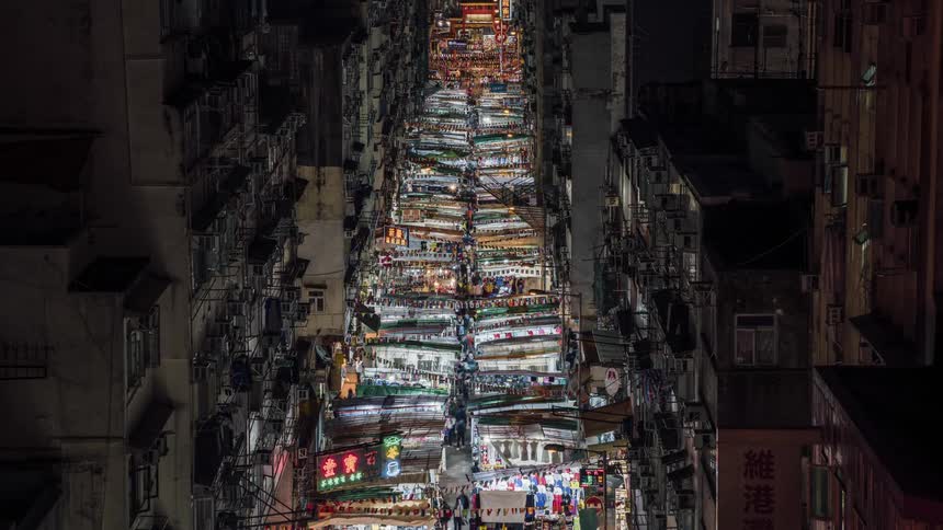 Aerial view of the city with tall buildings and people filling the market street at night