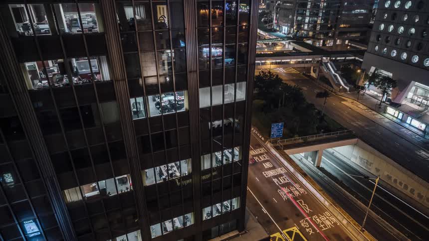 Exterior view of office building and vehicles driving on highway at night