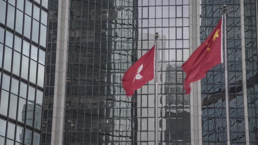 A company and chinese flag fly in the wind in front of the office building